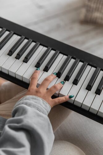 unrecognizable female musician playing synthesizer on couch