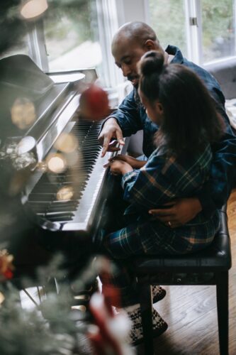 black little girl playing piano with father